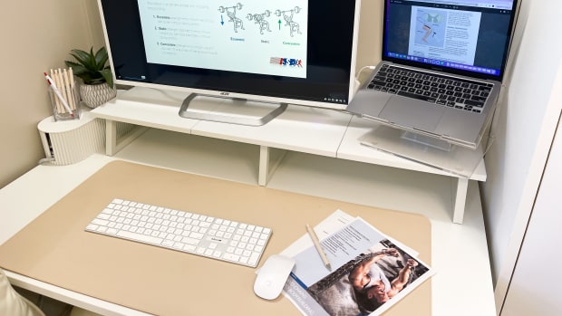 laptop and second screen on desk with study materials for ISSA bodybuilding course on screen. paper printouts of study materials and a pencil are on the righthand side of a mouse and keyboard